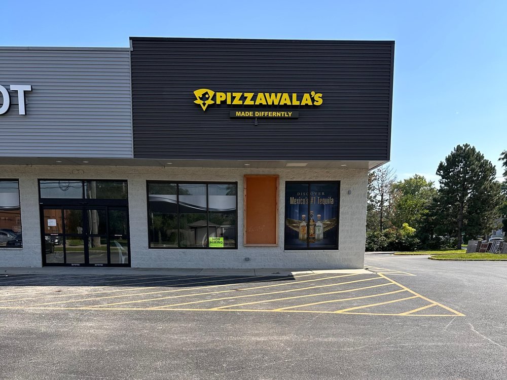 Yellow illuminated channel letters on the storefront fascia at Pizzawala's