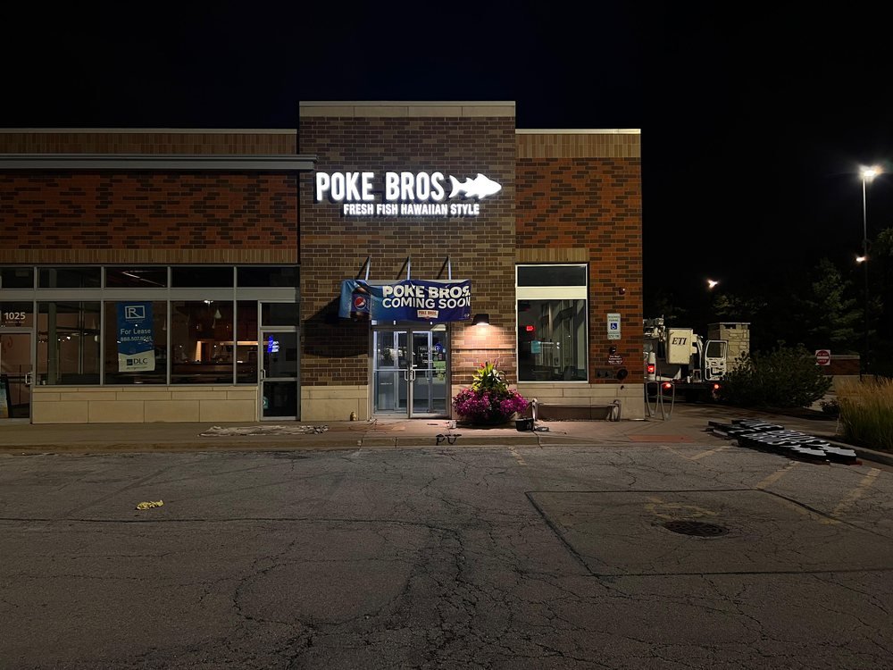 Poke Bros illuminated channel letters on a brick facade at night